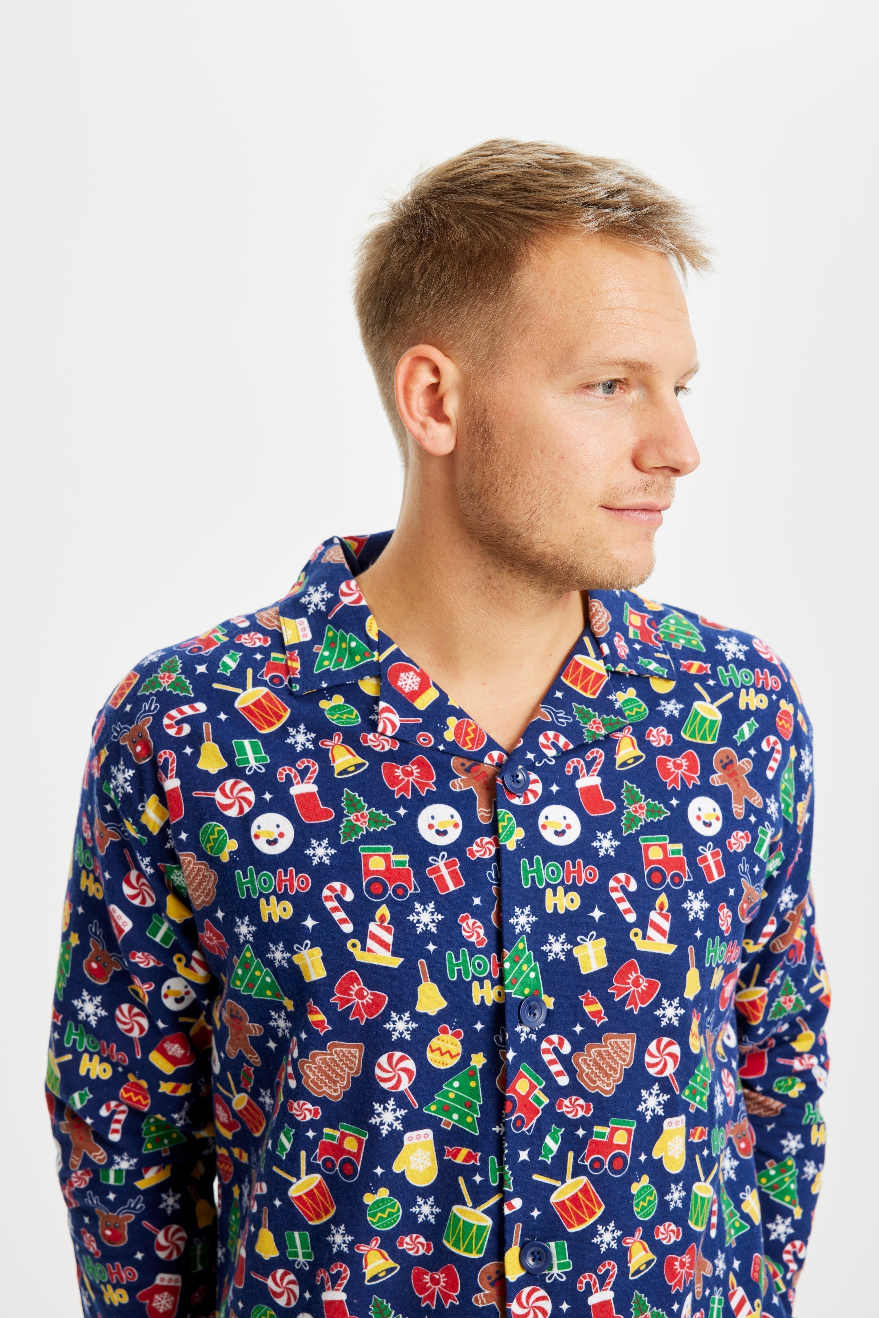 Un homme regardant sur le côté portant un pyjama bleu imprimé Noël.